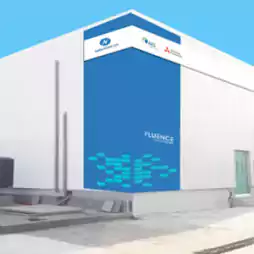 Modern white industrial building with blue accent wall featuring the Fluence logo and partner company logos on the upper corner, under a clear blue sky.