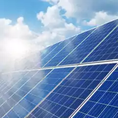 Rows of blue solar panels angled towards the sun under a partly cloudy sky, capturing sunlight for renewable energy.