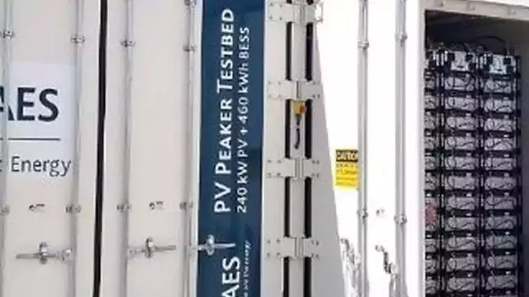 Close-up view of a PV Peaker Testbed container with 240 kW photovoltaic and 460 kWh battery energy storage system, showing the open door and battery racks inside.