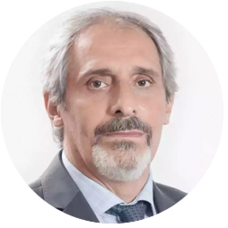 Portrait of an older man with gray hair and beard, wearing a suit and tie, posing against a plain white background.