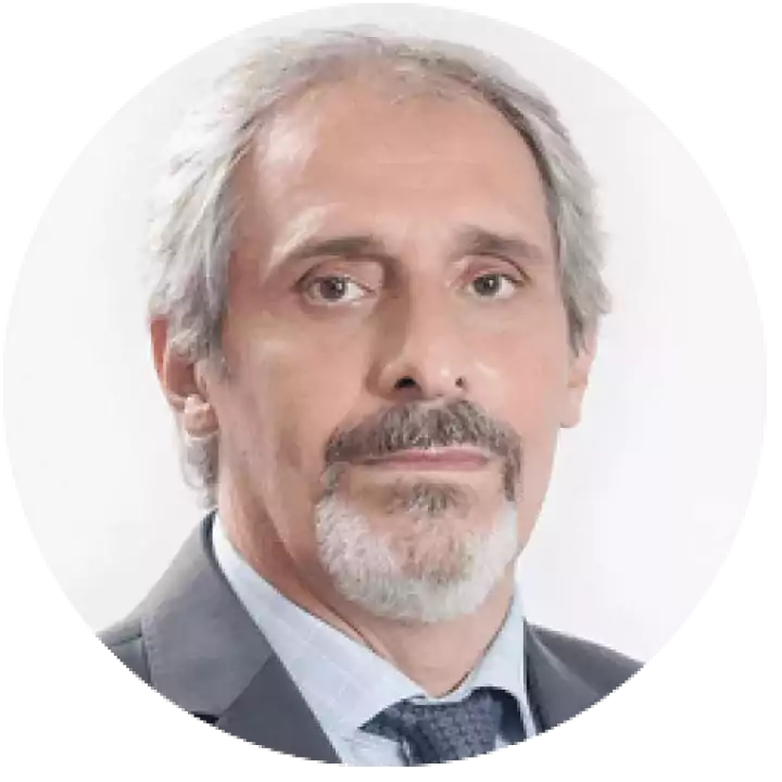 Portrait of an older man with gray hair and beard, wearing a suit and tie, posing against a plain white background.