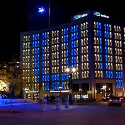 AES Indiana office building illuminated with blue and white lights at night, with cars and streetlights visible in the foreground.